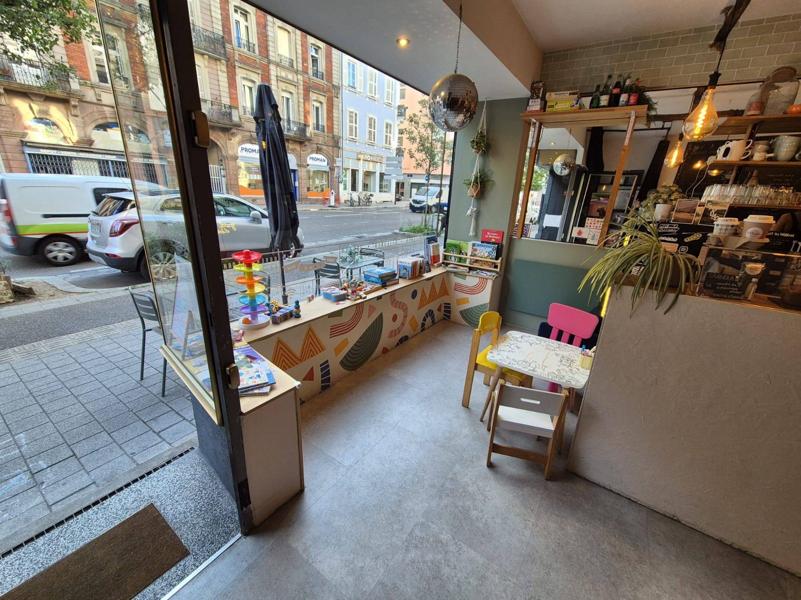 Le coin des enfants près de la vitrine : table et chaises à leur taille, jouets et livres à disposition