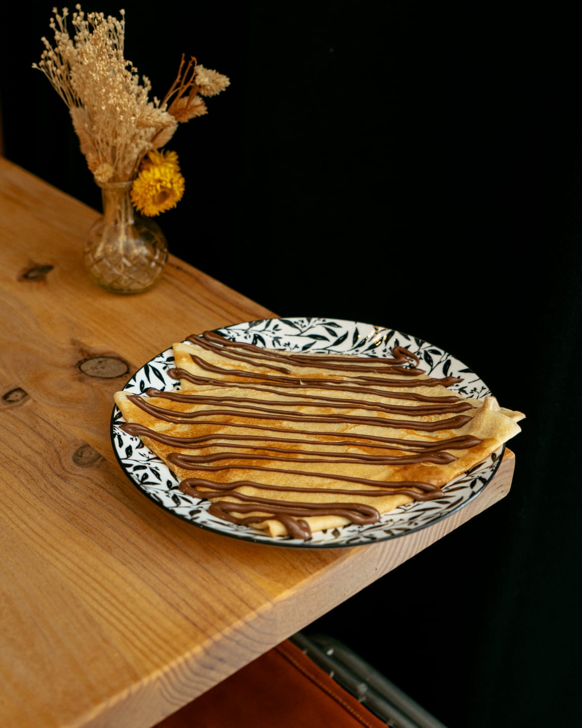 Crêpe froment nappée de Nutella sur une assiette à motifs de feuillage
